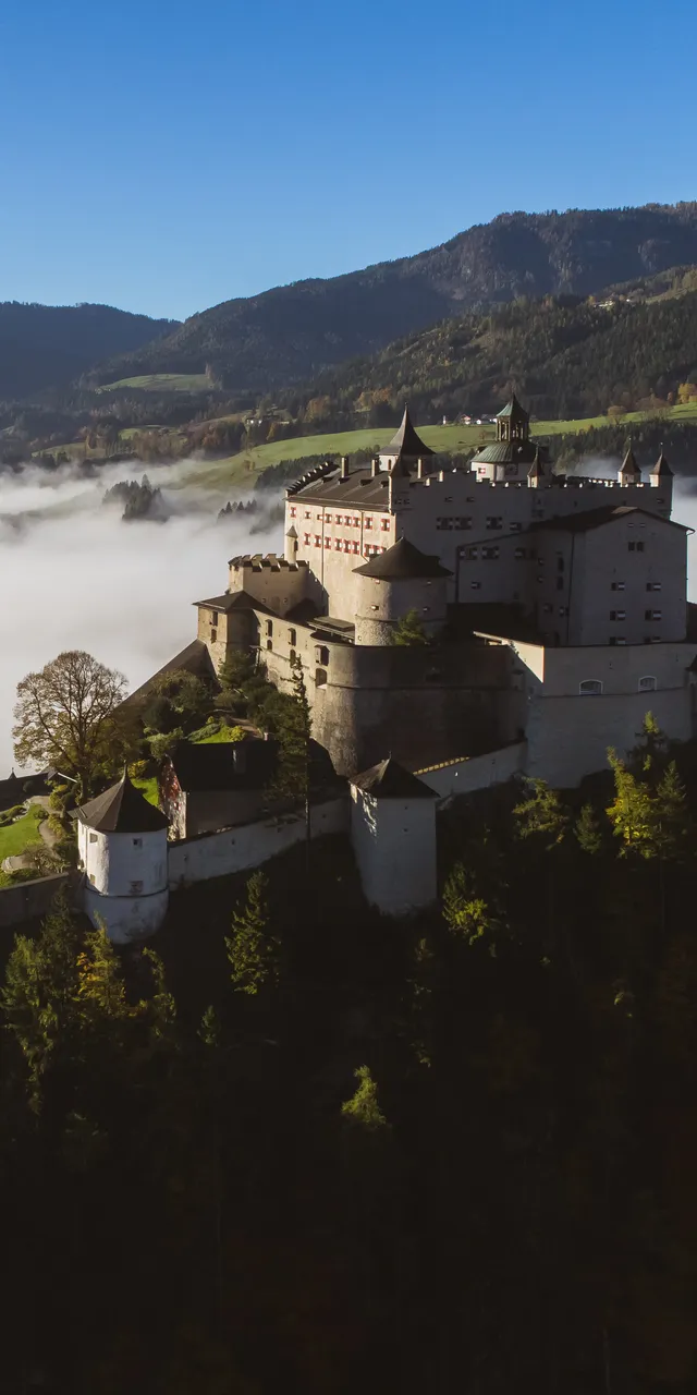 Castello di Hohenwerfen su una montagna circondato da nebbia e vista sulla valle alpina