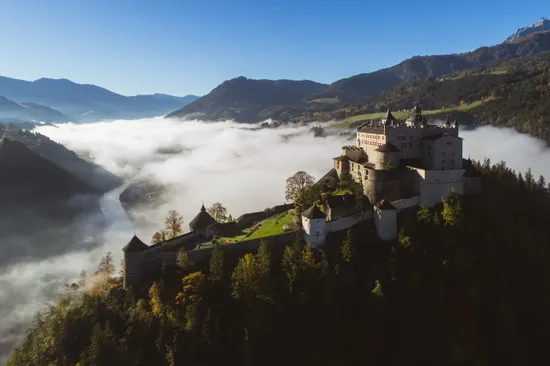 Castello di Hohenwerfen su una montagna circondato da nebbia e vista sulla valle alpina