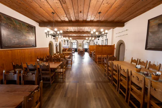 Sala da pranzo rustica con tavoli e sedie in legno, lampadari e soffitto in legno