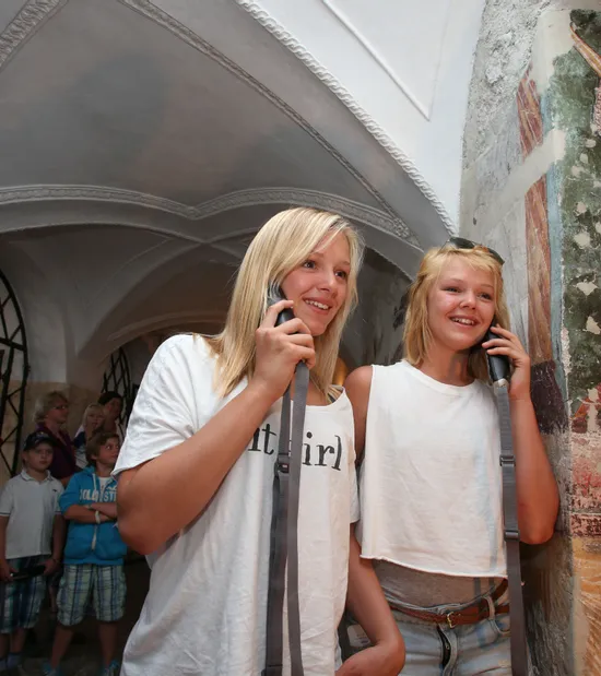 Teenager-Mädchen mit Audioguides in einem historischen Gebäude mit mittelalterlichem Wandgemälde