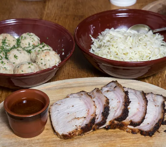 Roast pork slices with gravy, dumplings, and sauerkraut in bowls