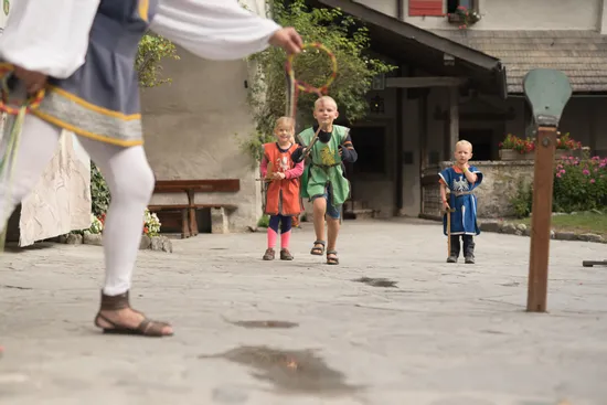 Bambini in costumi medievali giocano a un gioco tradizionale in un cortile in pietra