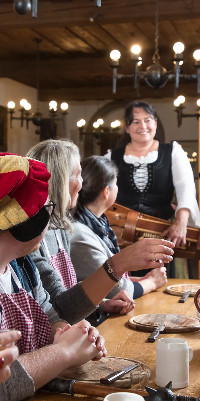 Banchetto medievale con musicisti e ospiti in abiti tradizionali in una sala scarsamente illuminata