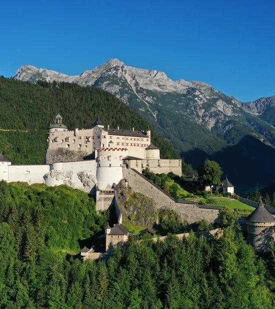 Storico castello di Hohenwerfen su collina boscosa con montagne sullo sfondo a Salisburgo, Austria