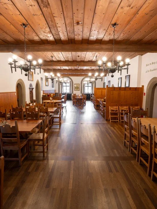 Rustic dining hall with wooden tables and chairs, chandeliers, and wooden ceiling
