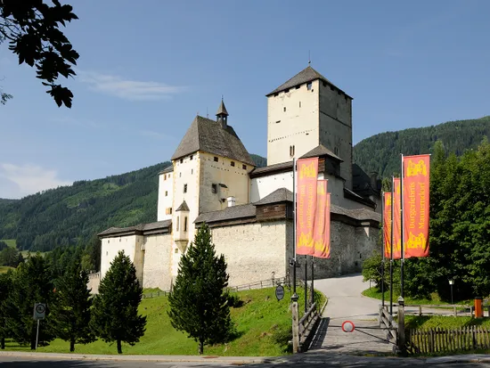 Castello di Mauterndorf con torri medievali e bandiere colorate nelle Alpi austriache
