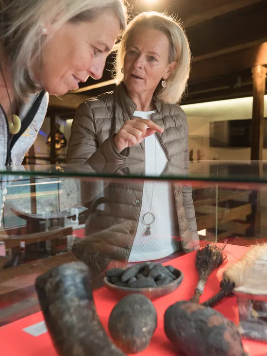 Zwei Frauen betrachten traditionelle Artefakte in einer Museumsvitrine