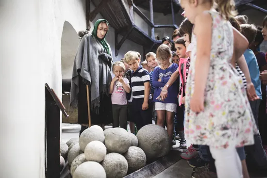 Group of children on historical museum tour observing stone cannonballs