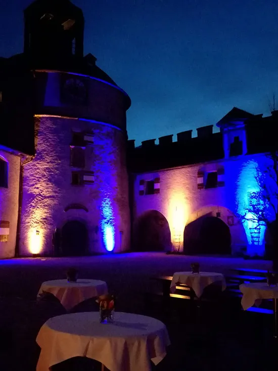 Historischer Innenhof nachts mit blauen und orangefarbenen Lichtern beleuchtet