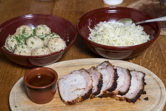 Fette di arrosto di maiale con sugo, gnocchi e crauti in ciotole