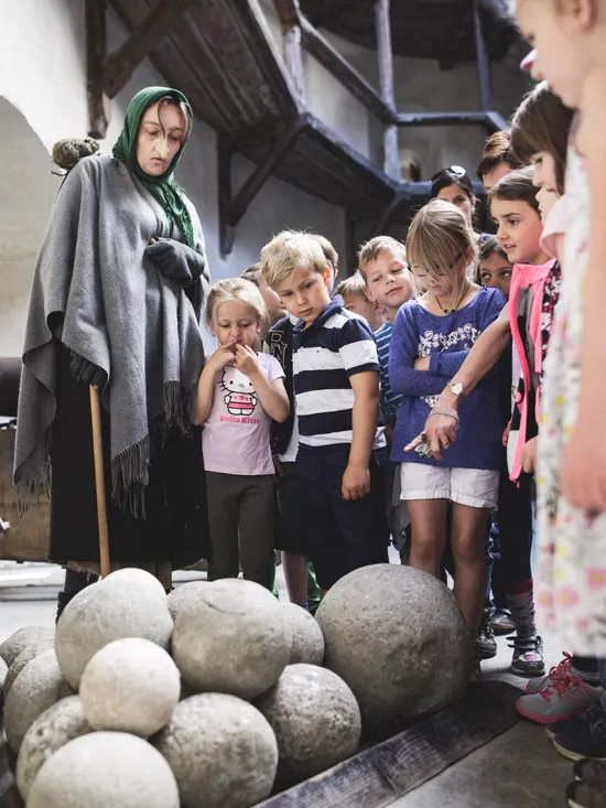 Group of children on historical museum tour observing stone cannonballs