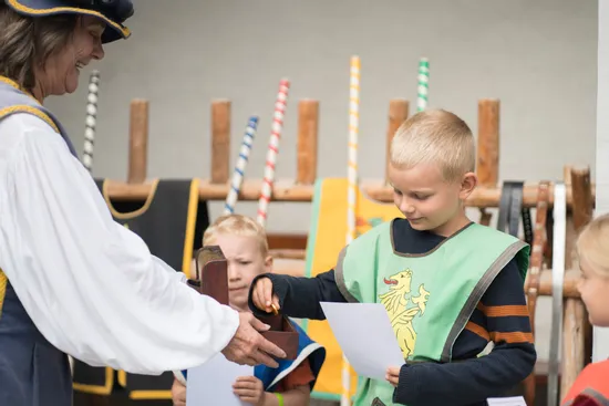 Junge im Mittelalterkostüm erhält Urkunde bei Themenveranstaltung mit Kindern