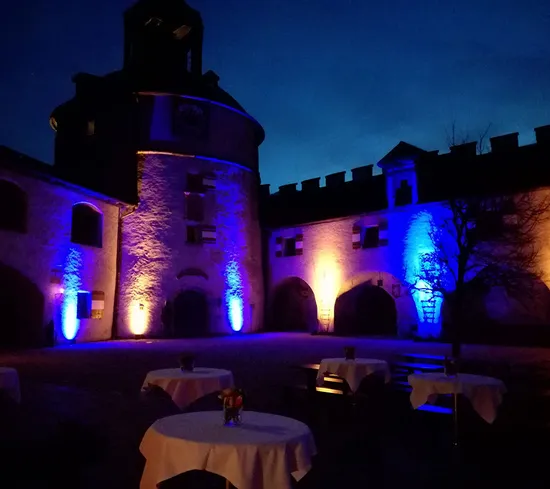 Historic courtyard lit with blue and orange lights at night