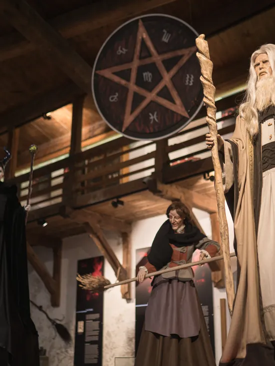 Lebensechte Hexen- und Zaubererfiguren in einem Fantasy-Museum mit Holzinnenraum ausgestellt