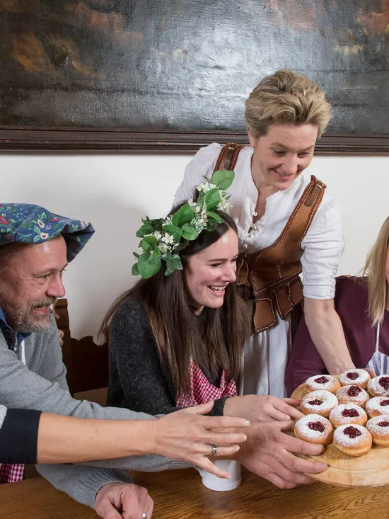 Group of people in festive outfits sharing traditional German jam-filled donuts