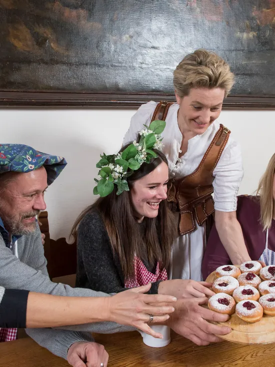 Gruppe in festlicher Kleidung teilt traditionelle deutsche Berliner mit Marmelade