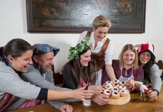 Gruppo in abiti festivi condivide krapfen tedeschi con marmellata