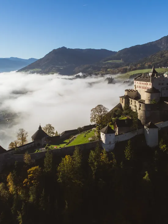 Castello di Hohenwerfen su una montagna circondato da nebbia e vista sulla valle alpina