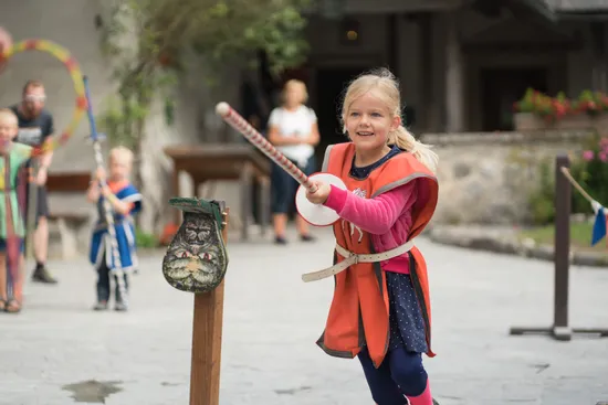 Bambina sorridente in costume medievale gioca a un torneo durante una festa storica
