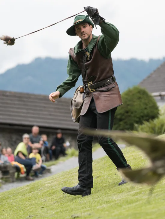 Falkner in Mittelalterkleidung trainiert Greifvogel bei einer Flugshow im Freien