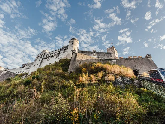 Storica fortezza Hohensalzburg su una collina con funicolare e cielo azzurro